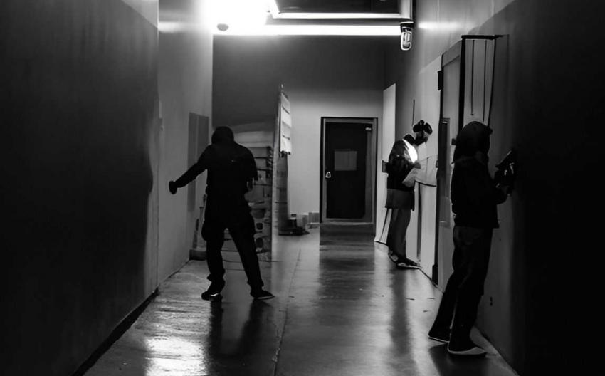 Black-and-white image of dark corridor with three people in it