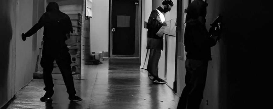 Black-and-white image of dark corridor with three people in it
